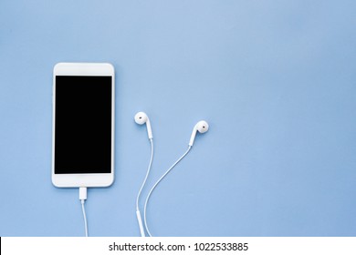 Smartphone with Blank Screen and Earphones on Blue Background Top View