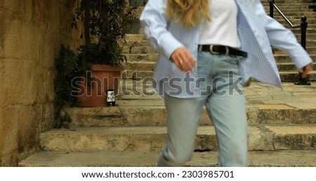 Smartphone with camera app running timer stand on stairs in antique street. Anonymous woman start shutter countdown on phone and run to shoot place to take selfie in touristic place.