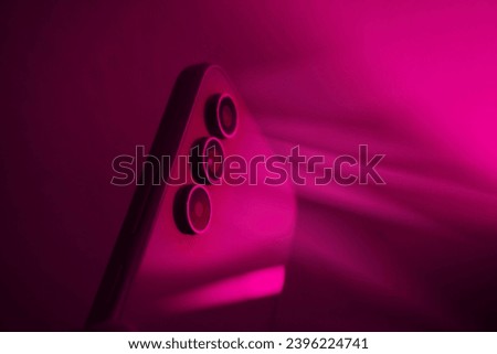 
Smartphone camera close-up 
view, objective lens effect on glass of mobile cell,Shiny modern phone in neon lights background.