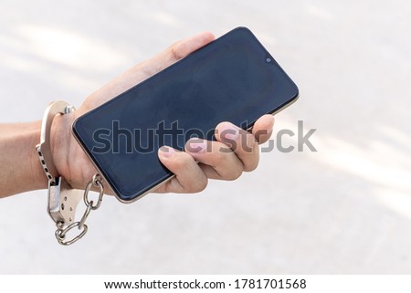 Smartphone chained to handcuffed in hand. Mobile phone addiction concept.