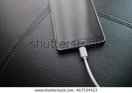 Smartphone Charging On black sofa texture background