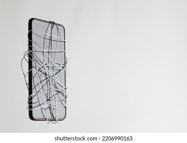 smartphone coiled metal wire in the hands of a man, gray-green background, censorship of social networks. cancel cultural ban, erase