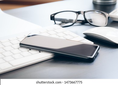 Smartphone and computer keyboard on office table close up