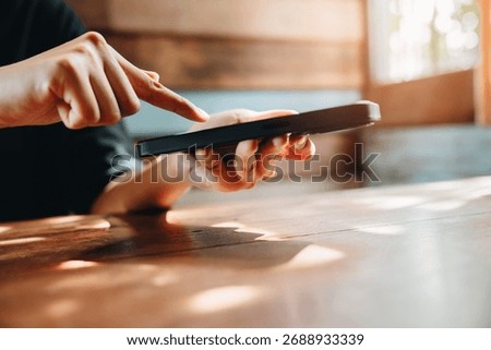 Smartphone concept. Person Using Touchscreen Smartphone While Sitting at Wooden Table in Cozy Indoor Environment