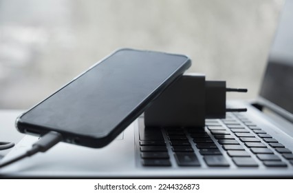The smartphone is connected to the laptop via USB cable. Smart cell phone being charged.  power unit . 