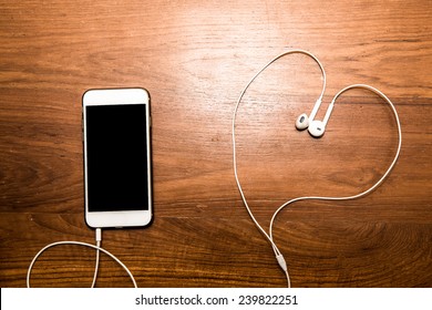 Smartphone with earphone on wood table. - Powered by Shutterstock