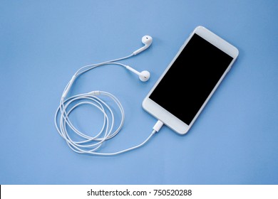 Smartphone with Earphones on Blue Background Top View