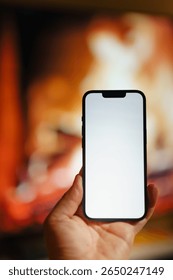 smartphone empty white screen mockup hand hold fireplace warm background