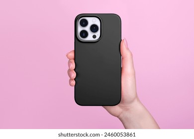 Smartphone in female hand in black silicone cover isolated on pink background phone case mock up in monochrome colours back view
