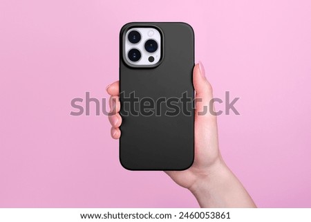 Smartphone in female hand in black silicone cover isolated on pink background phone case mock up in monochrome colours back view