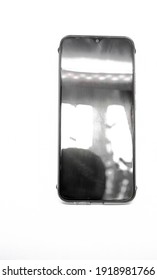 A smartphone with a front-facing camera at the top of the screen and bright highlights on it