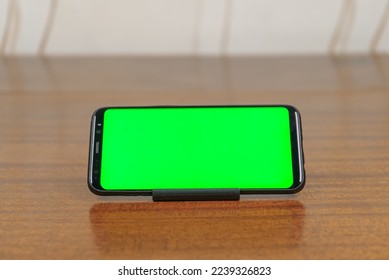 Smartphone with green screen display for mock-ups to use in a graphic design. Cell phone is isolated