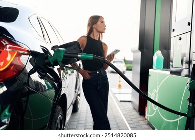 Smartphone in hands. A young woman at a gas station with her car. - Powered by Shutterstock