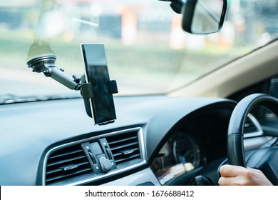 Smartphone hanging on phone holder in a car. Stick on the front car mirror.