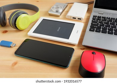 Smartphone with Headphones and ebook reader and other electronic gadgets on wooden background.
