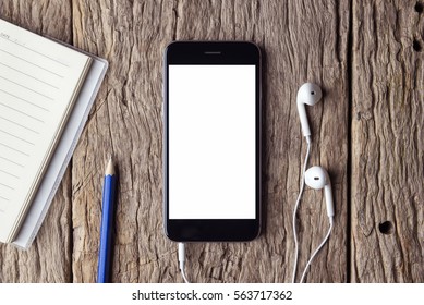 Smartphone with headphones on wooden table.  white screen.