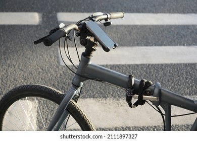 Smartphone holder for bike on  pedestrian crossing background. Cell phone holder on bicycle to use gps for guidance in city center 