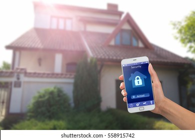 Smartphone with home security app in a hand on the building background
