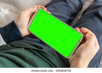 Smartphone With A Hromakey In The Hands Of A Child. Phone A For Keying Is Holding Kid Top View Close Up. Smartphone With A Green Screen In Hand Child .