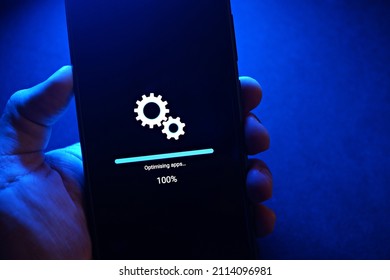Smartphone installing system update in progress against blue light background.