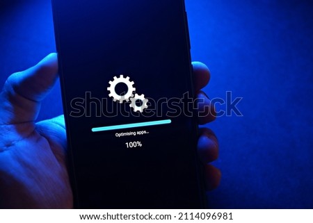 Smartphone installing system update in progress against blue light background.
