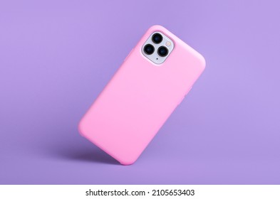 Smartphone iPhone 11 and 12 Pro max in pink silicone case falls down back view, phone case mockup isolated on purple background