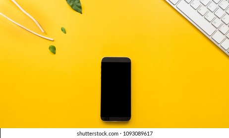 Smartphone  with keyboard and leaves on yellow background business  concept desk table copyspace - Shutterstock ID 1093089617