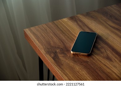 the smartphone is lying on a wooden table