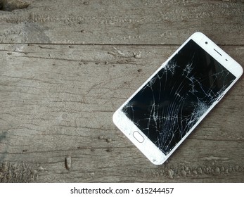 Smartphone mobile with a broken screen on wood background