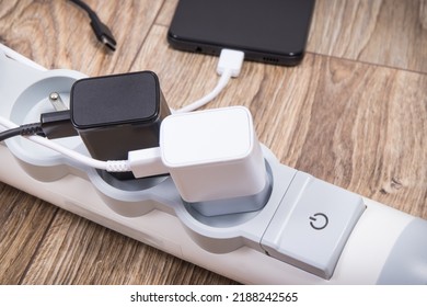 Smartphone, mobile phone and chargers connected to electrical power strip. Various devices charging concept