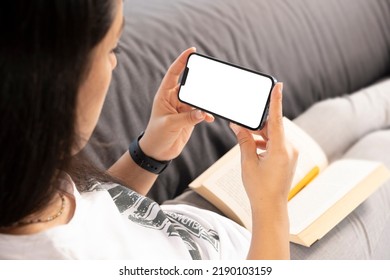 Smartphone Mock Up, Caucasian Woman Have A Break To Reading Book And Holding Smartphone Mock Up. Portrait Of Young Lady Watching Movie Or Attending Online Meeting From Her Home With Her Cell Phone.