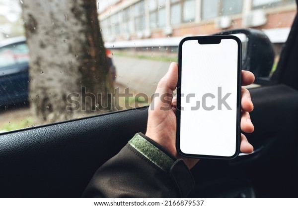 Smartphone mockup, car driver holding mobile\
phone with blank white screen in\
vehicle