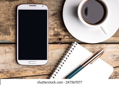 Smartphone with notebook and cup of strong coffee on wooden background. Cell phone with writing set with espresso - Powered by Shutterstock