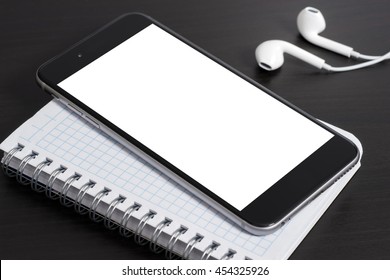 Smartphone and notepad on dark table, headphones