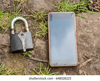 Smartphone, old key, lock - security, caution - idea, concept. Against the background of the old stone.
