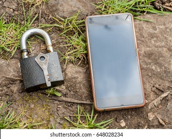 Smartphone, old key, lock - security, caution - idea, concept. Against the background of the old stone.