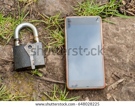 Smartphone, old key, lock - security, caution - idea, concept. Against the background of the old stone.
