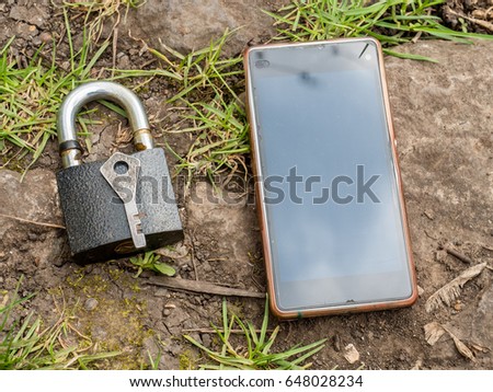 Smartphone, old key, lock - security, caution - idea, concept. Against the background of the old stone.