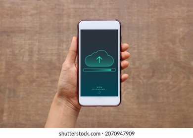 Smartphone on hand opening cloud uploading concept on phone screen. woman or man hand upload from mobile phone to store data on server. - Shutterstock ID 2070947909