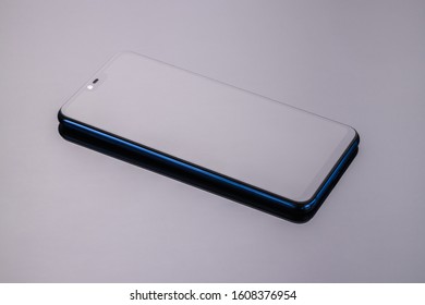 Smartphone on a mirror surface with reflection, blue, glossy side surfaces.