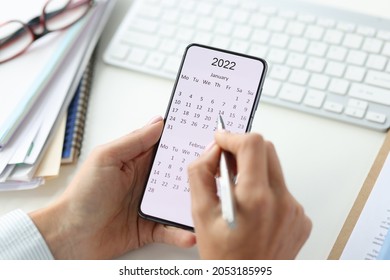Smartphone auf dem Bildschirm mit Kalender für 2022 Stift in weiblichen Händen
