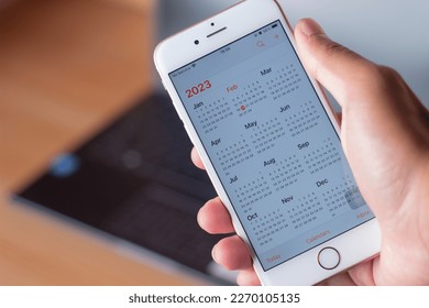 Smartphone on screen with calendar for 2023 in male hands