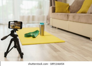 Smartphone on a tripod recording video with a equipment for home workout. Concepts of online fitness training or vlogging. - Powered by Shutterstock