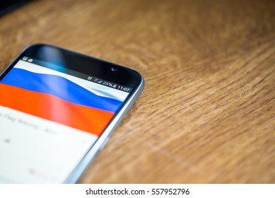 Smartphone on wooden background with 5G network sign 25 per cent charge and Russia flag on the screen.