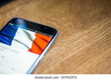 Smartphone on wooden background with 5G network sign 25 per cent charge and France flag on the screen.