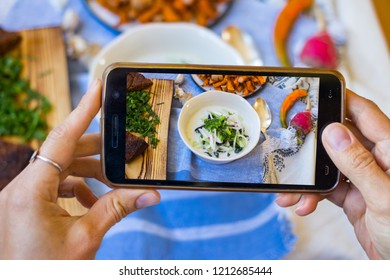 Smartphone Photography Of Food. Woman Hands Holds Mobile Phone And Take Or Make Beautiful Trendy Food Photo For Social Networks Or Blogging. Okroshka Russian Traditional Cold Soup