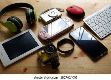 Smartphone with portable game consoles and ebook reader and other electronic gadgets on wooden background.Top view. - Shutterstock ID 1827624005