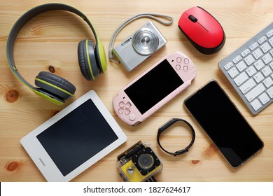 Smartphone with portable game consoles and ebook reader and other electronic gadgets on wooden background.Top view. - Shutterstock ID 1827624617