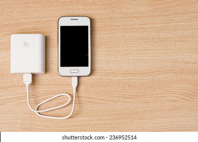 Smartphone With A Power Bank Charger On Wood Background