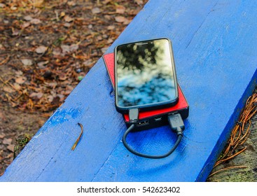 Smartphone And Powerbank On A Blue Board